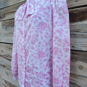 May include: A white long-sleeve blouse with a pink floral pattern. The blouse has a bow tie collar and button closure.