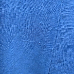 May include: Close-up of a blue fabric with a subtle texture. The fabric has a slight sheen and appears to be woven.