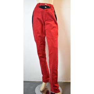 May include: Red denim jeans with black accents on the waist and side panels. The jeans have a classic five-pocket design and a straight leg fit. The waist features a black yoke and two gold-colored buttons.