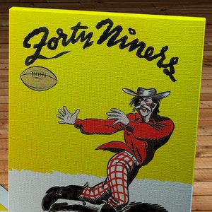 Può includere: Poster vintage con un cowboy dei cartoni animati con una camicia rossa e pantaloni a quadri che cerca di prendere un pallone da football. Le parole "Forty Niners" sono in nero su sfondo giallo. Il testo in basso recita "Forty Niners vs. Brooklyn Dodgers September 22, 1946."