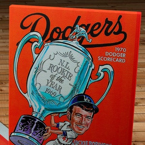 May include: A vintage 1970 Dodgers Scorecard featuring a cartoon illustration of a baseball player holding a trophy that reads "N.L. Rookie of the Year 1969". The scorecard is orange with black text and a 25¢ price tag.