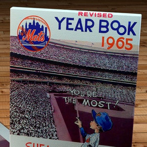 May include: A vintage New York Mets yearbook from 1965. The cover features a photo of Shea Stadium with a crowd of fans, a cartoon of a Mets player, and the text "REVISED YEAR BOOK 1965 YOU'RE THE MOST! SHEA STADIUM NEW YORK PRICE FIFTY CENTS".
