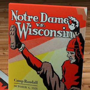 Op de afbeelding: Een vintage poster die reclame maakt voor een American footballwedstrijd tussen Notre Dame en Wisconsin. De poster heeft een rood-wit kleurenschema met een footballspeler die de bal trapt. De tekst op de poster luidt "Notre Dame vs. Wisconsin", "Camp Randall", "October 6, 1928", en "25c per Copy".
