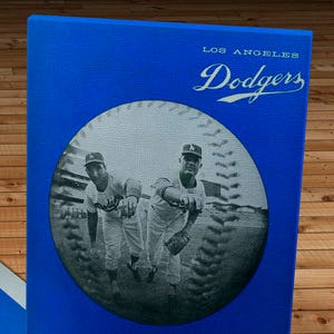 May include: A blue and red baseball scorecard with a photo of three baseball players in uniform. The scorecard is for the Los Angeles Dodgers and is dated 1965. It says "Official Dodger Score Card 25c".
