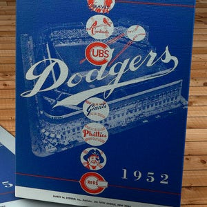 Może przedstawiać: Winietkowy program baseballowy z 1952 roku dla Brooklyn Dodgers. Program ma niebieskie tło z białym obrysem boiska baseballowego. Logo Dodgers znajduje się w środku boiska, otoczone logo innych drużyn, w tym Braves, Cardinals, Giants, Phillies i Reds.