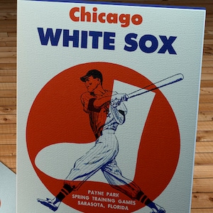 Könnte beinhalten: Ein Vintage-Baseball-Scorebook der Chicago White Sox aus dem Jahr 1961 mit einem roten Kreis und einem Baseballspieler, der einen Schläger schwingt. Das Scorebook kostet 15 Cent.
