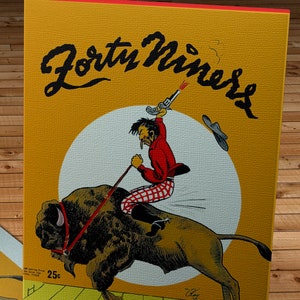 Può includere: Un poster vintage che pubblicizza una partita tra i Forty Niners e i Buffalo Bisons il 2 novembre 1946. Il poster presenta un'immagine di un cowboy che cavalca un bufalo, con una pistola in mano e un cappello da cowboy che gli vola via dalla testa. Il poster è giallo con un cerchio bianco al centro.