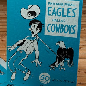 May include: A vintage program cover for a Philadelphia Eagles vs. Dallas Cowboys football game. The cover features a cartoon illustration of a cowboy being dragged by an eagle. The text on the cover reads "Philadelphia Eagles Dallas Cowboys 50 Cents Official Program Franklin Field November 25, 1962".