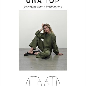 Puede incluir: Un patr&oacute;n de costura para una blusa verde de manga larga llamada "URA TOP". El patr&oacute;n incluye instrucciones y est&aacute; disponible en tallas XS-3XL. La imagen muestra un boceto plano de la blusa desde el frente y la espalda.