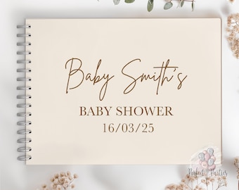 May include: A cream-colored spiral-bound guest book featuring brown text that reads Baby Smith's BABY SHOWER 16/03/25. The cover has a clean, neutral design with a metallic silver wire binding along the left side for a functional, flat-lay layout.
