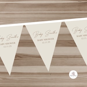 May include: Three beige triangle-shaped pennants with the text "Baby Smith's Baby Shower 12.11.23" on each pennant.