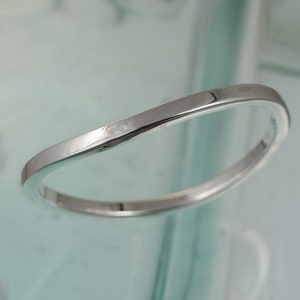 May include: A simple, silver, curved wedding band.