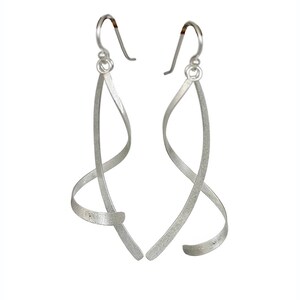 May include: Silver dangle earrings with a twisted, wire design.
