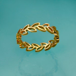 May include: A gold ring featuring a leaf design. The ring is crafted from thin metal and has a delicate appearance.