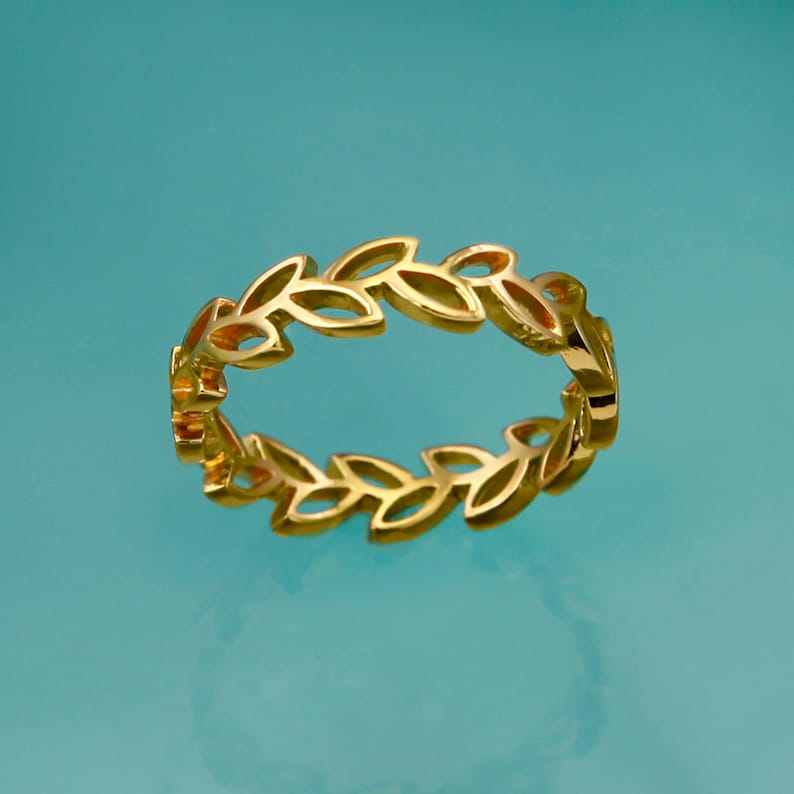 May include: A gold ring with a leaf design. The ring is made of a thin metal and has a delicate look.