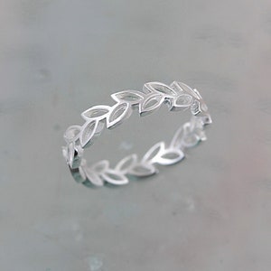 May include: A silver ring featuring a delicate design of leaves around the band.