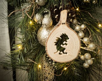 Könnte beinhalten: Ein hölzerner Weihnachtsbaumschmuck in Form eines Baumstamms mit einem ausgeschnittenen Design eines Igels. Der Schmuck hängt an einer grünen Kiefern-Girlande mit goldenen Glitzer-Ornamenten und weißen Lichtern.