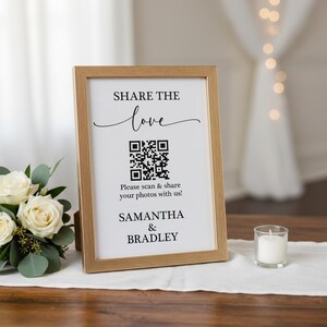 May include: A framed sign with the text "SHARE THE love" and a QR code. Below the QR code is the text "Please scan & share your photos with us!" and the names "SAMANTHA & BRADLEY". A small candle sits to the right.