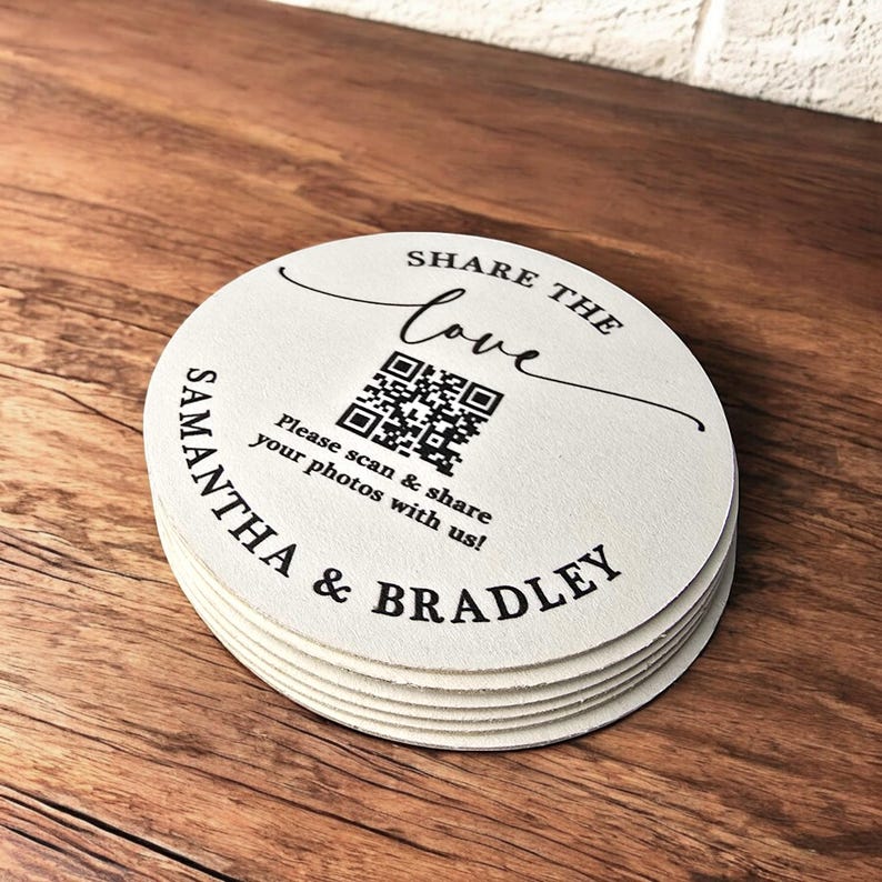 May include: White round coasters with black text that reads "SHARE THE love" and a QR code. Below the QR code is the text "Please scan & share your photos with us!" and the names "SAMANTHA & BRADLEY".