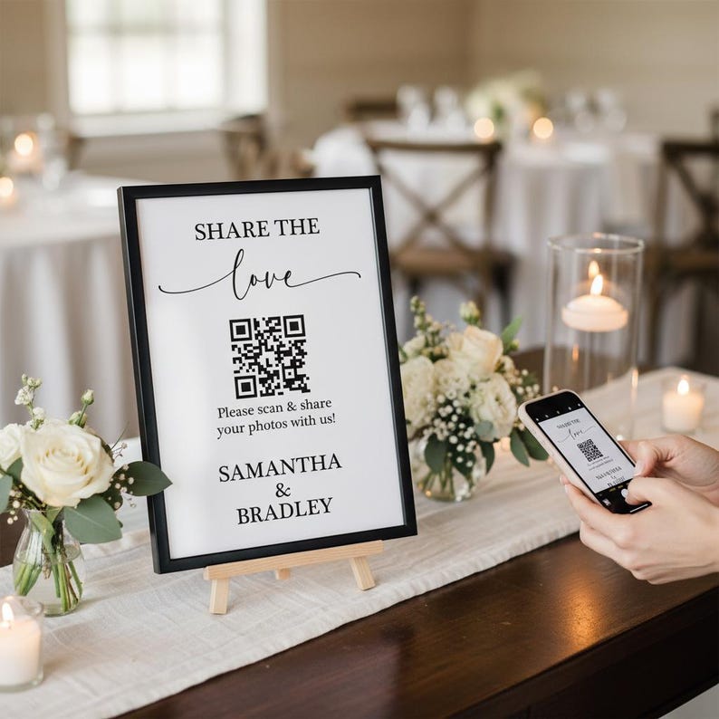 May include: A black framed sign with the text "SHARE THE love" and a QR code. Below the QR code is the text "Please scan & share your photos with us!" and the names "SAMANTHA & BRADLEY". The sign is on a small wooden easel.