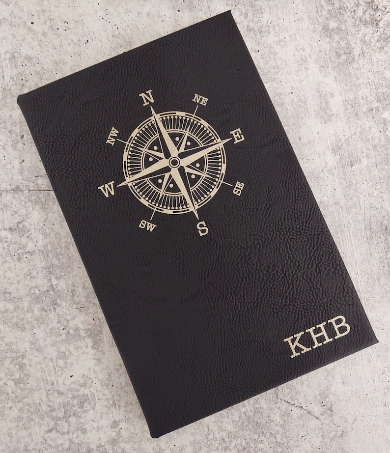 Faux Leather Journal featuring a rose compass top center and your initials in the bottom right.  Pictured is a black cover which engraves to gold foil.