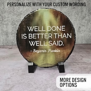 May include: A round slate coaster with a forest scene and the quote "Well done is better than well said. - Benjamin Franklin".