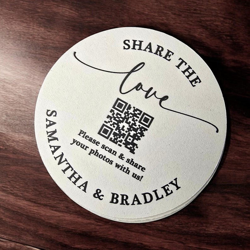 May include: A white round paper coaster with black text that says "Share the love" and a QR code. Below the QR code is the text "Please scan & share your photos with us!" and "Samantha & Bradley".