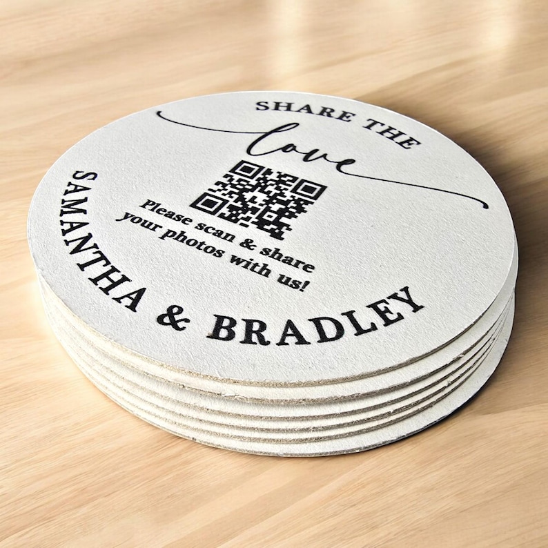 May include: White round coasters with black text that reads "Share the Love" in a stylised cursive font. A black and white QR code is in the centre of the coaster. Below the QR code is the text "Please scan & share your photos with us!" and below that is the text "Samantha & Bradley".
