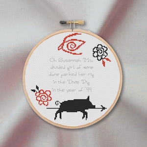 Könnte beinhalten: Stickerei auf einem runden Rahmen mit einem schwarzen Schwein, roten Blumen und dem Text "Oh Susannah Mio divided girl of mine done parked her rig in the Dixie Dig in the year of '99".