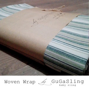 May include: A woven baby wrap in a green and white striped pattern, packaged in brown paper with a label that reads "by GuGaSling baby sling".