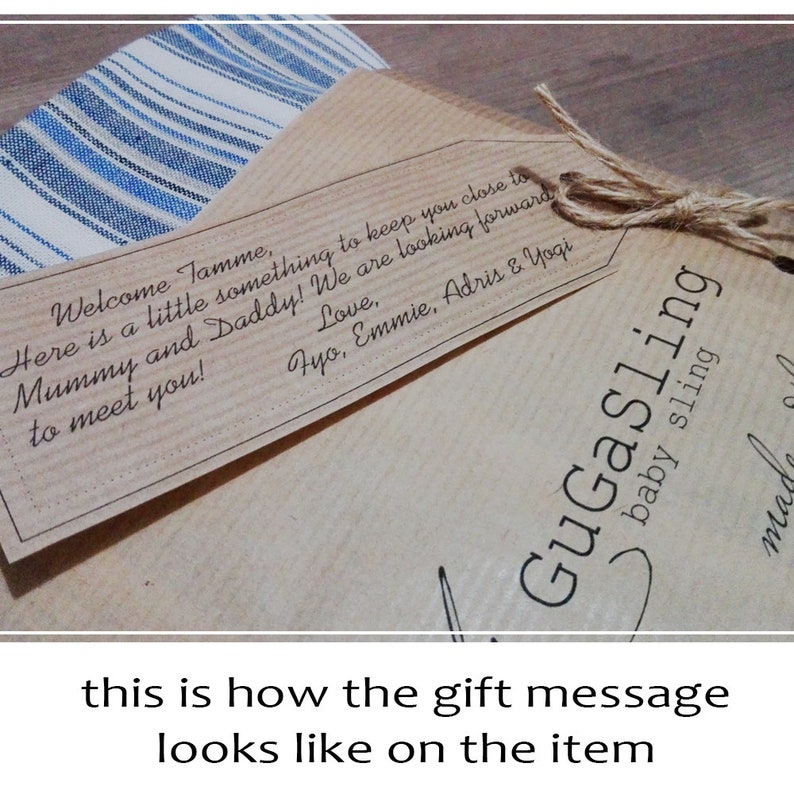 May include: A brown paper gift bag with a handwritten gift tag that reads "Welcome Tamme, Here is a little something to keep you close to Mummy and Daddy! We are looking forward to meet you! Love, Fyo, Emmie, Adris & Yogi". The bag is tied with twine and has a label that reads "GuGaSling baby sling".