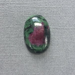 May include: Oval-shaped green and pink gemstone cabochon with a smooth, polished surface.