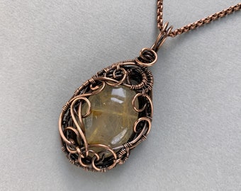 May include: A copper wire wrapped pendant featuring a clear, faceted, golden quartz stone.