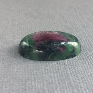 May include: Oval-shaped green and pink gemstone cabochon with a smooth, polished surface.