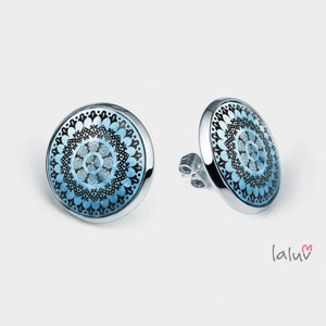 Puede incluir: Un par de pendientes de botón de plata con un diseño de mandala azul y negro.