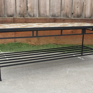 May include: A black metal coffee table with a tiled top and a lower shelf. The tile is a mix of brown, white, and beige.