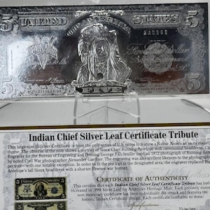 May include: A silver certificate tribute to Indian Chief Running Antelope. The certificate features a portrait of Running Antelope with a headdress and the text "Indian Chief Silver Leaf Certificate Tribute".