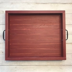 May include: A red wooden serving tray with black metal handles. The tray is made of wood planks and has a rustic look.