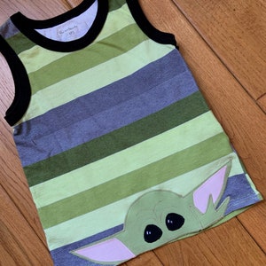 Pode incluir: Camisola de al&ccedil;as listrada em verde, cinza e verde claro com uma aplica&ccedil;&atilde;o verde, rosa e preta de um personagem com olhos grandes. A etiqueta na camisa diz "Granimals" e "STMP3".