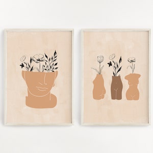 Pu&ograve; includere: Due stampe d'arte minimaliste con sfondo beige. La prima stampa presenta una testa umana stilizzata con fiori che crescono dalla parte superiore. La seconda stampa presenta tre figure umane stilizzate con fiori che crescono dalla parte superiore.
