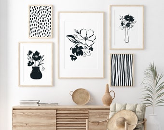 Può includere: Un design di interni per un soggiorno con un mobile in legno chiaro, una sedia intrecciata, un tappeto intrecciato e una collezione di stampe d'arte astratte in bianco e nero sul muro.