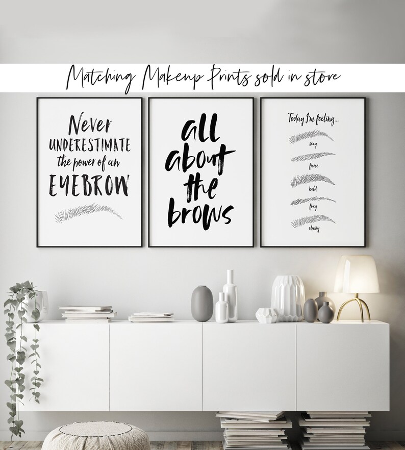 May include: Three black and white framed prints with eyebrow-themed quotes and illustrations. The first print says "Never underestimate the power of an eyebrow" with a single eyebrow illustration. The second print says "All about the brows". The third print says "Today I'm feeling..." with five eyebrow illustrations labeled "stay", "fierce", "bold", "fray", and "classy".
