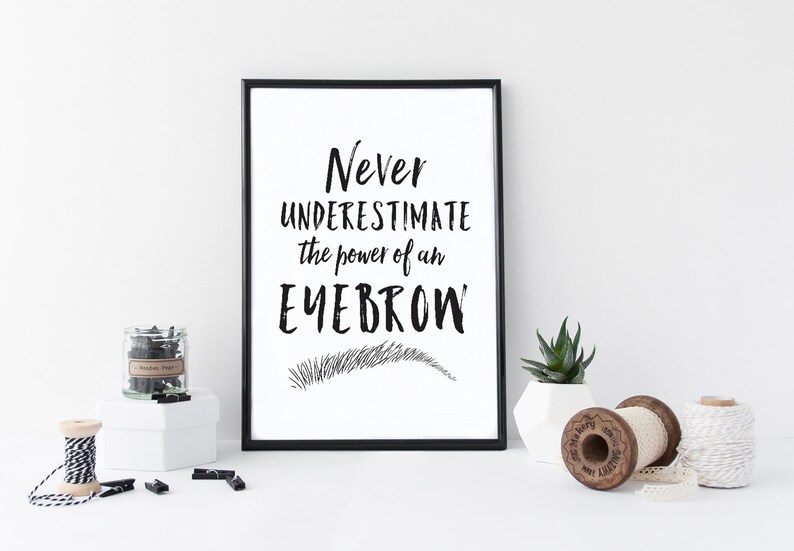 May include: Black and white printable wall art with the text "Never underestimate the power of an eyebrow" and a stylized drawing of an eyebrow.