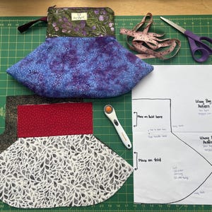 May include: A sewing project in progress, featuring a blue and purple patterned bag, fabric pieces, scissors, a rotary cutter, and a measuring tape. A pattern for a "Wung Bag" is also visible.
