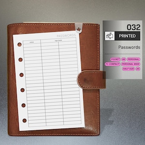 May include: A brown leather planner with a white password log sheet inserted. The sheet is held in place by a star-shaped paper clip. The planner has a snap closure. The text "PASSWORDS" is visible on the sheet. A printed label shows "Passwords".