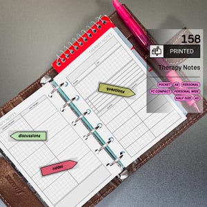 May include: Open therapy notes planner with a red spiral binding and a brown leather cover. The planner includes pages with lines and sections for notes, discussions, and questions. A pink pen rests on the pages, and sticky notes mark key sections.