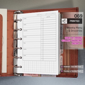 May include: A brown leather planner with a printed weekly menu and grocery list insert. The insert is labeled "MENU / GROCERIES" and includes sections for each day of the week. The planner also has tabs and the text "069 PRINTED Weekly Menu & Groceries".