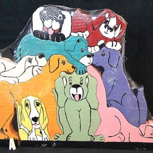 May include: A wooden puzzle featuring a collection of interlocking dog figures in various colors including yellow, green, blue, purple, red, white, and pink. The puzzle pieces are wrapped in clear plastic and include a small white letter A at the base.