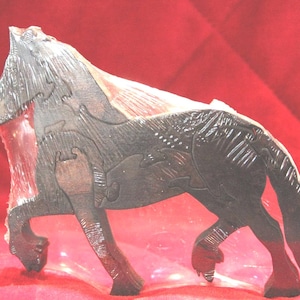 May include: A dark brown wooden puzzle shaped like a standing horse. The figure is composed of several interlocking wooden pieces that fit together to form the silhouette of a horse with a textured mane, tail, and defined legs in a side profile.