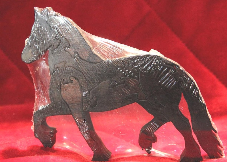 May include: A dark brown wooden horse puzzle featuring interlocking pieces with carved details on the mane, tail, and legs. The horse is depicted in a standing position with a textured surface finish, encased in a clear protective plastic film.